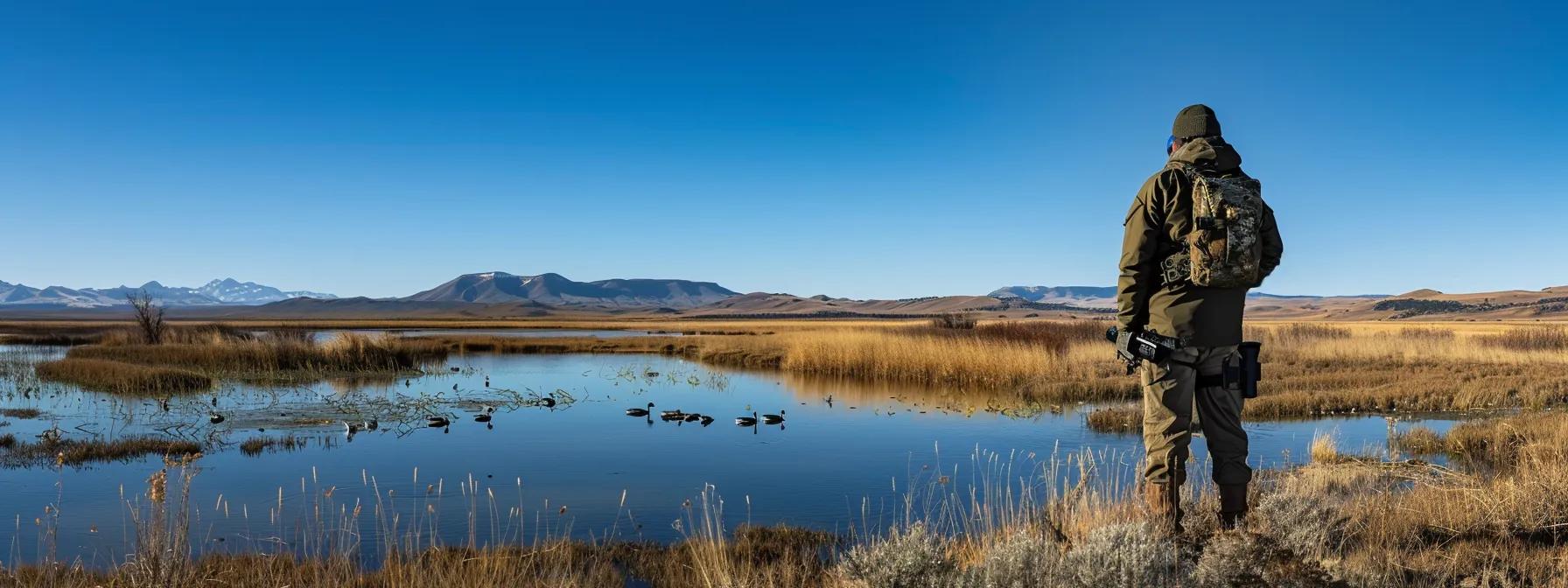 a waterfowl hunter stands confidently at the edge of a sprawling, designated wildlife habitat management area in wyoming, equipped with tactical gear and a detailed map, surrounded by expansive wetlands and distant mountains under a clear blue sky.